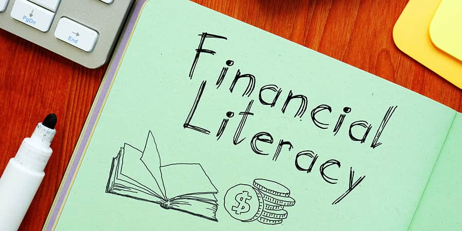 An open notebook resting on a desk with the words financial literacy.