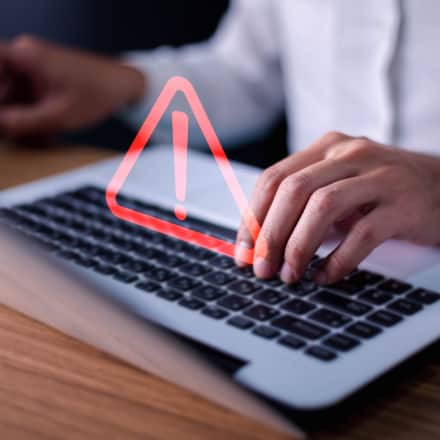 A watermark of a red warning sign over a man using a laptop.
