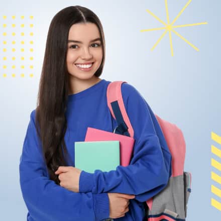 A smiling, young female student wearing a backpack and holdng books.