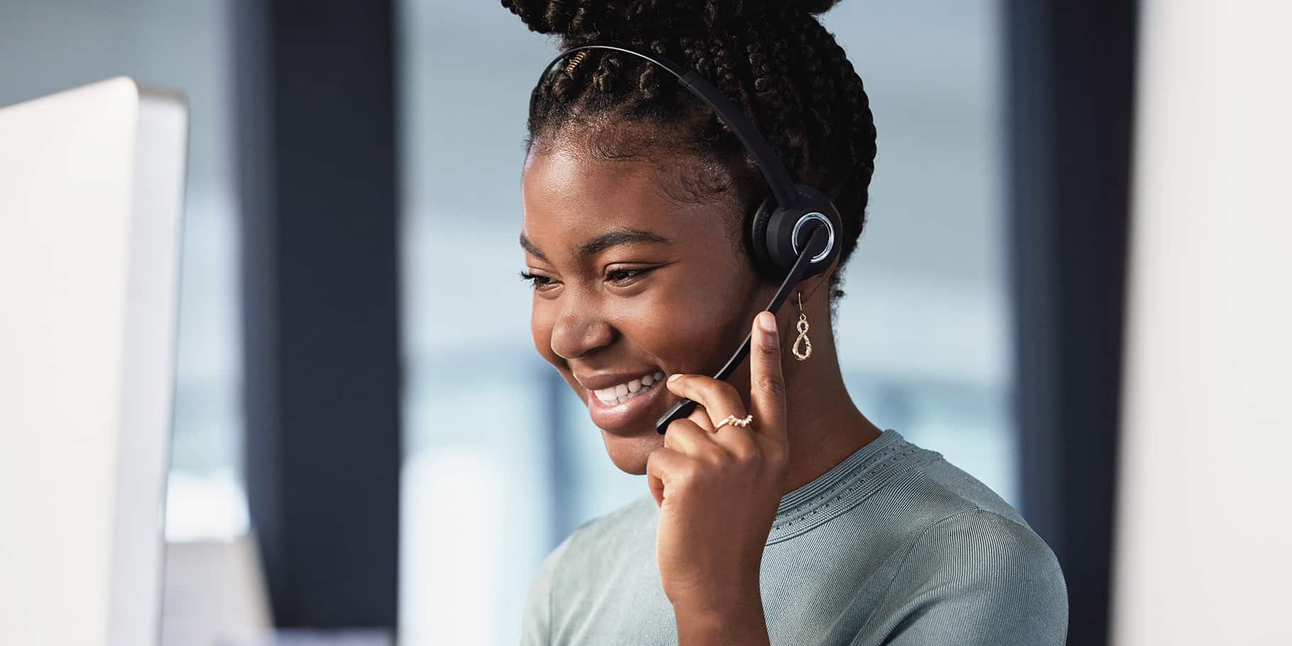 A smiling young African American woman on a phone headset.