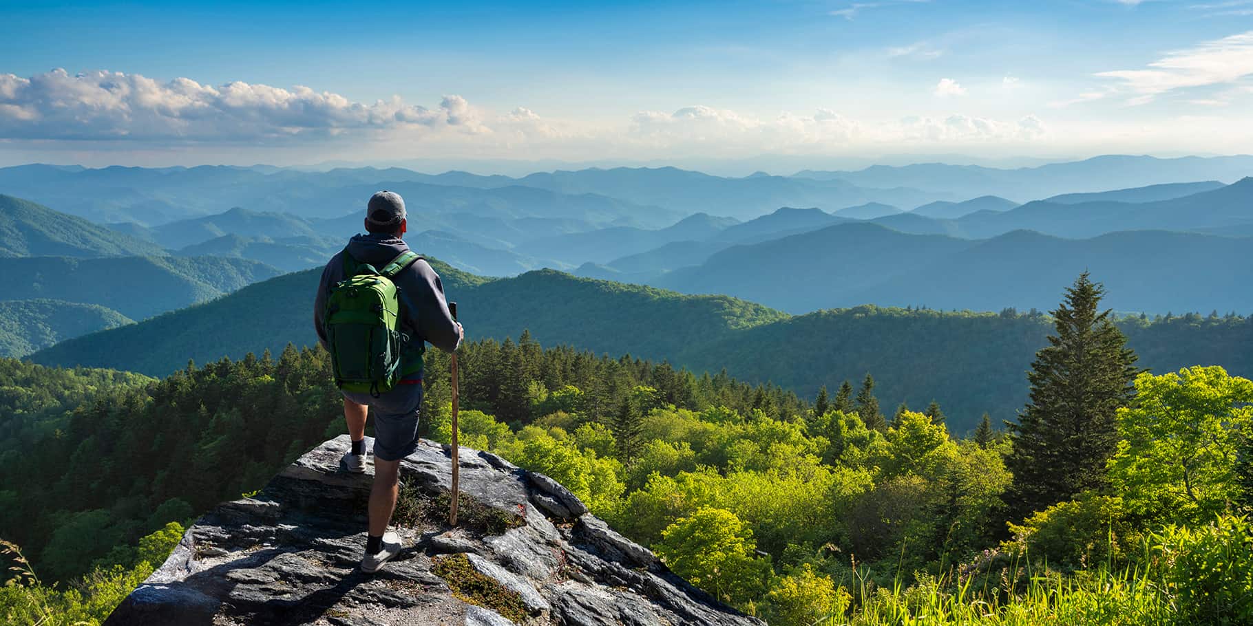 A man resting at the summit of a hike through a rocky mountain.