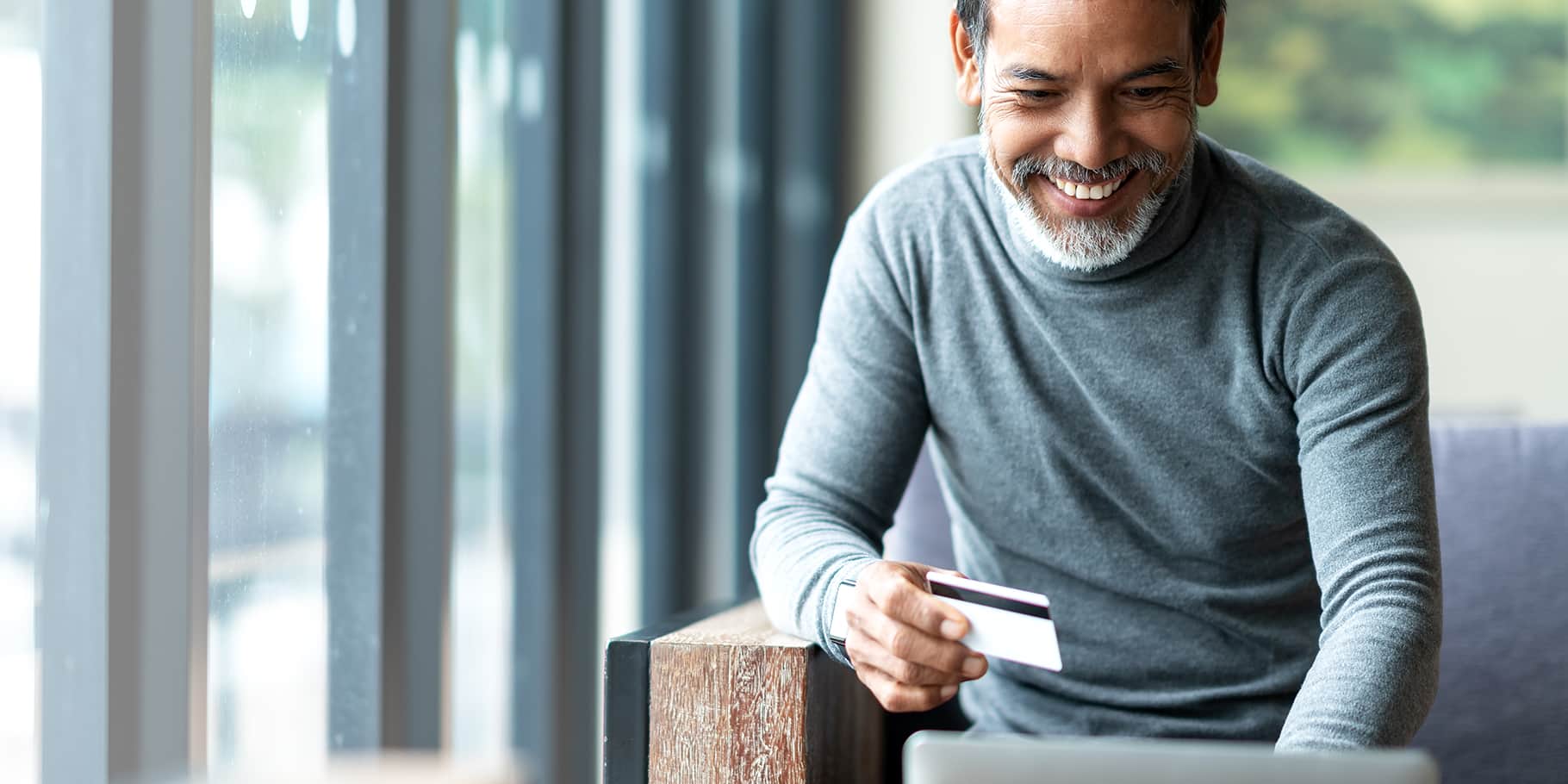 An middle-aged man smiling while using a card.