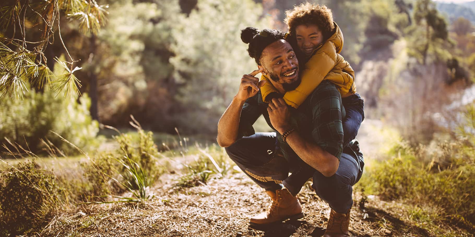 A young father and his son hiking along a trail.