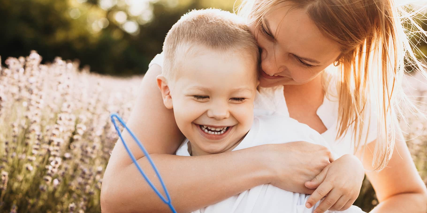 A young mother embracing her toddler in a wheat field.