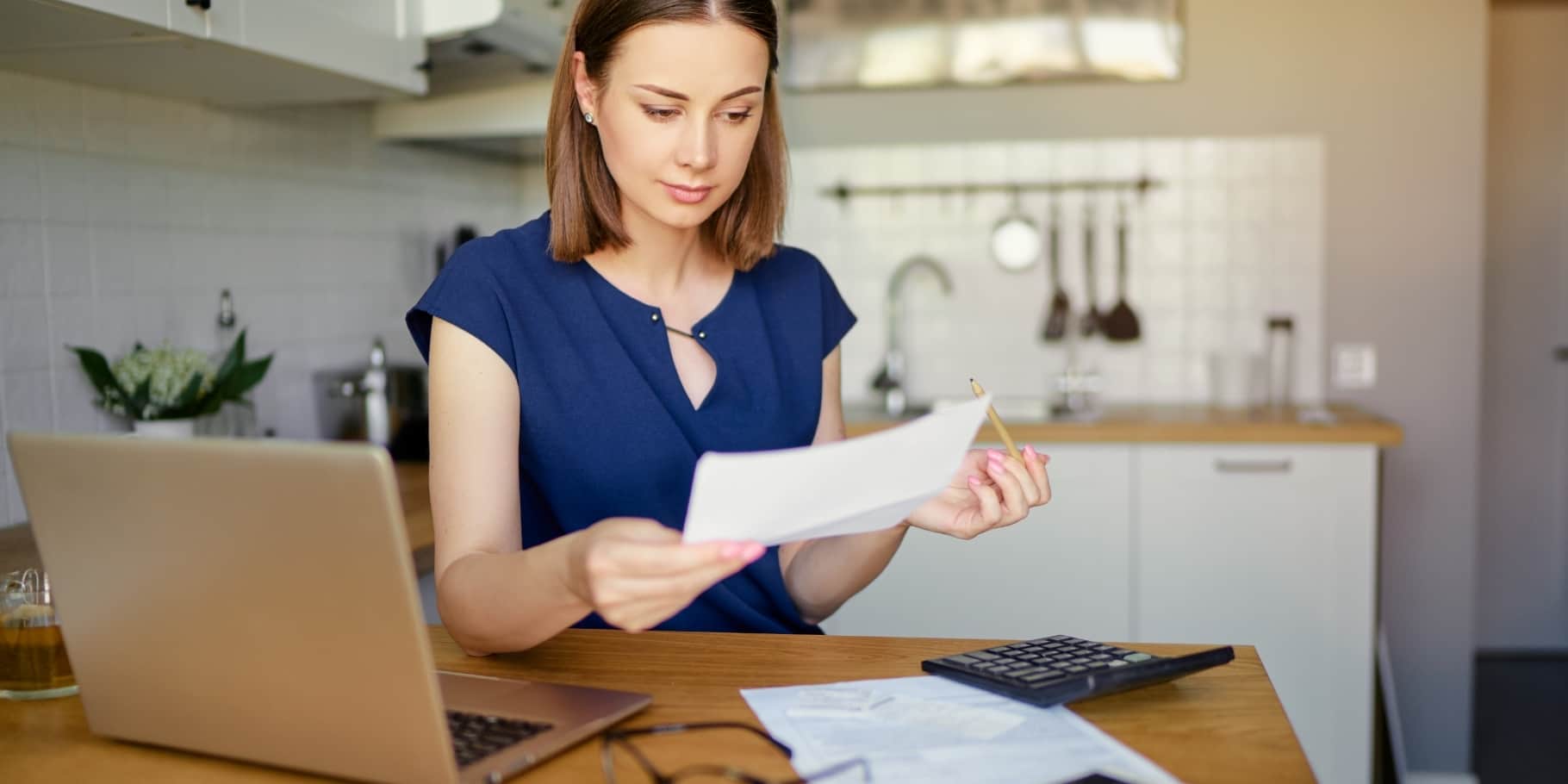 A woman looking over bills at a desk.