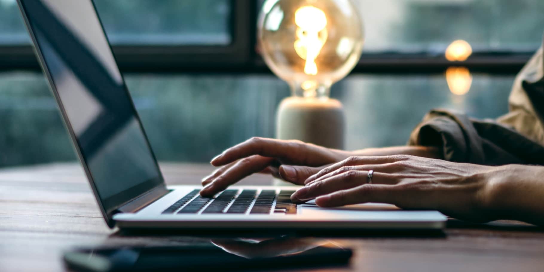 A male hand typing on a laptop.