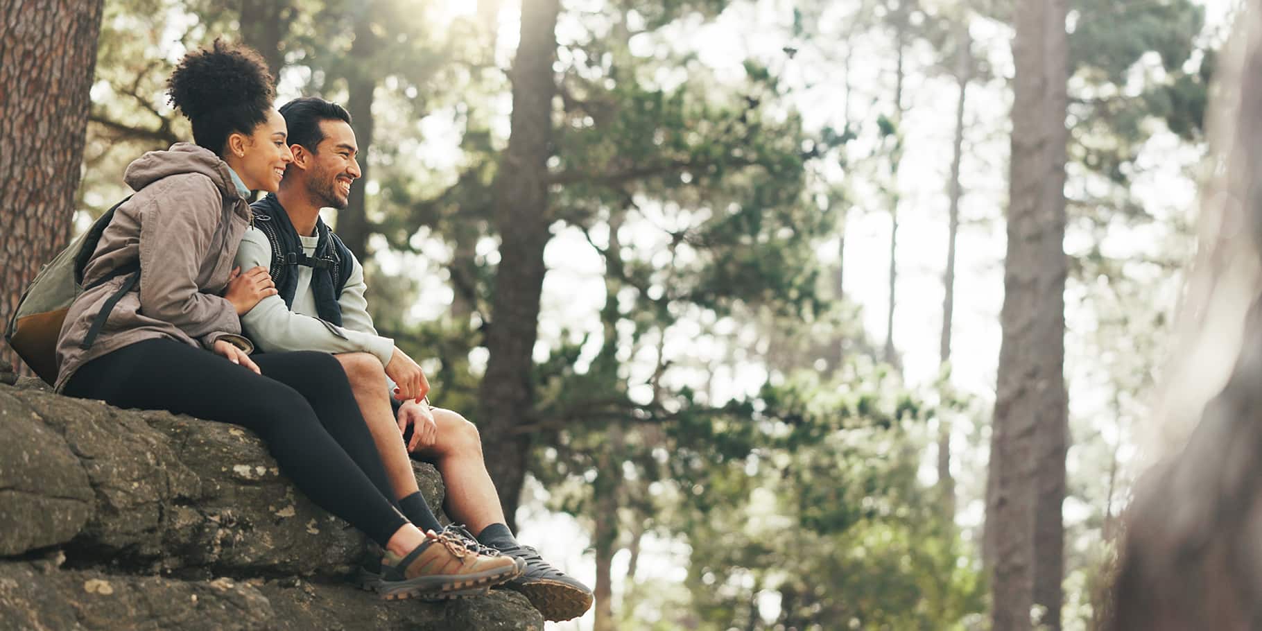 A couple resting on a rock in a hiking trail.