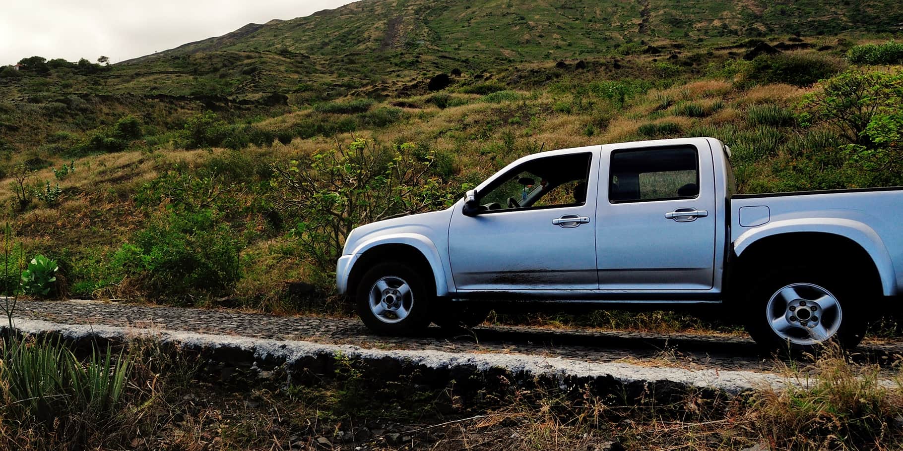 A silver pickup truck on a mountain trail.