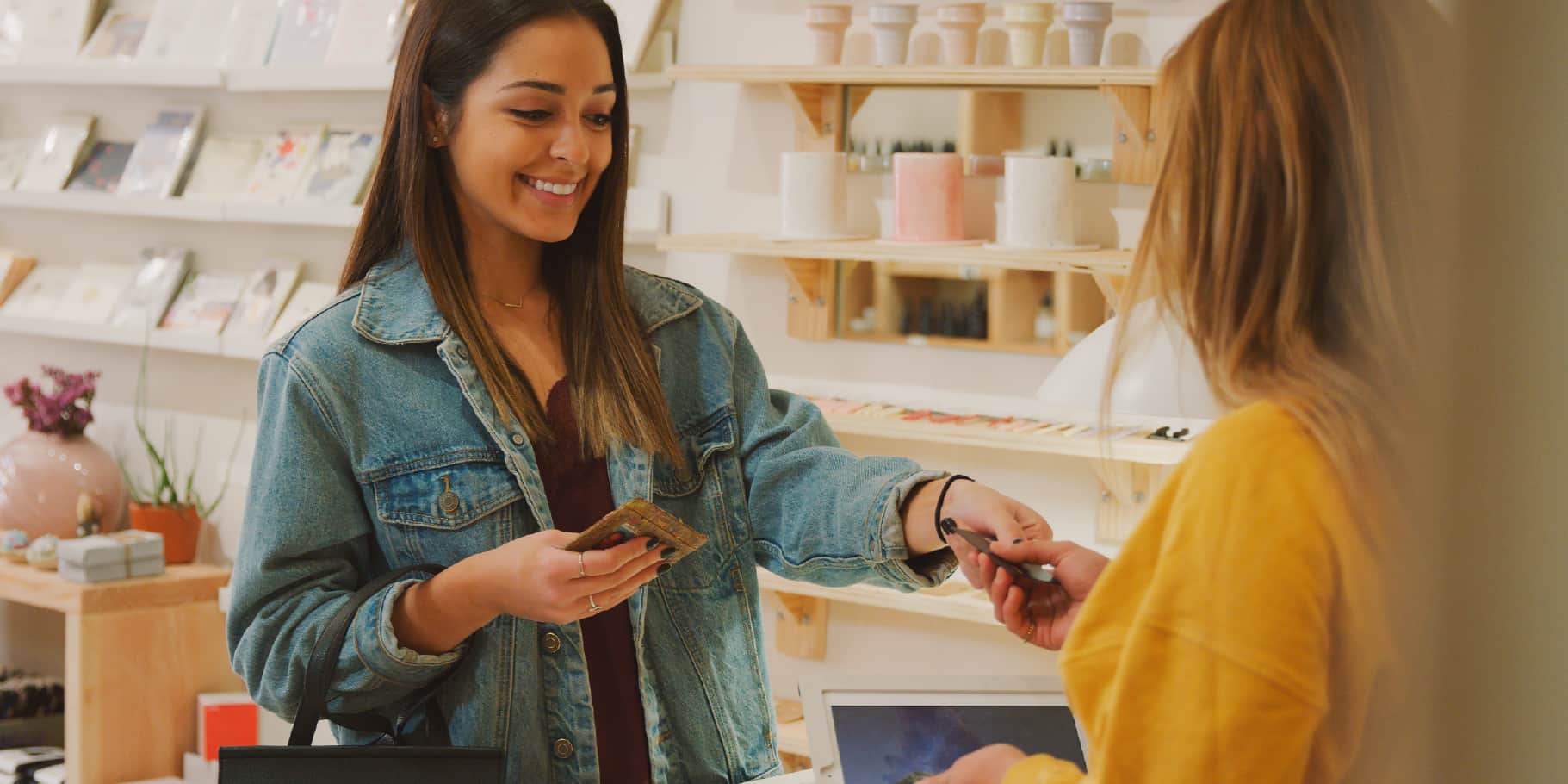 A happy young woman making a purchase with her debit card at a retail store.