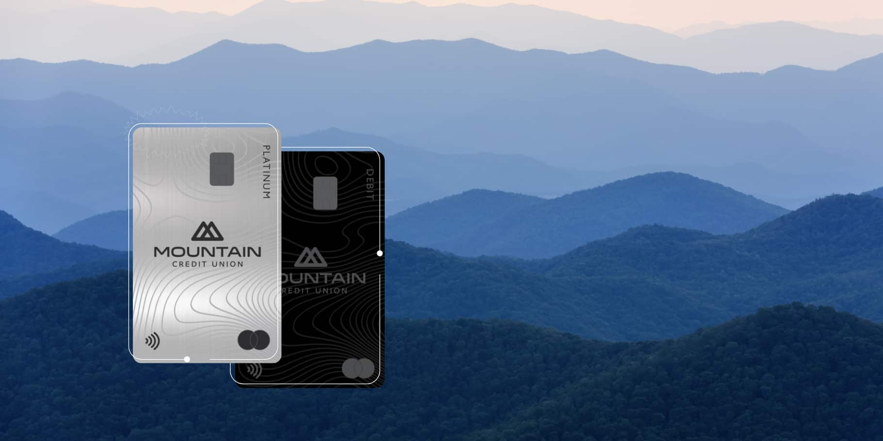 The Mountain Credit Union credit and debit cards in front of the Blue Ridge Mountains.