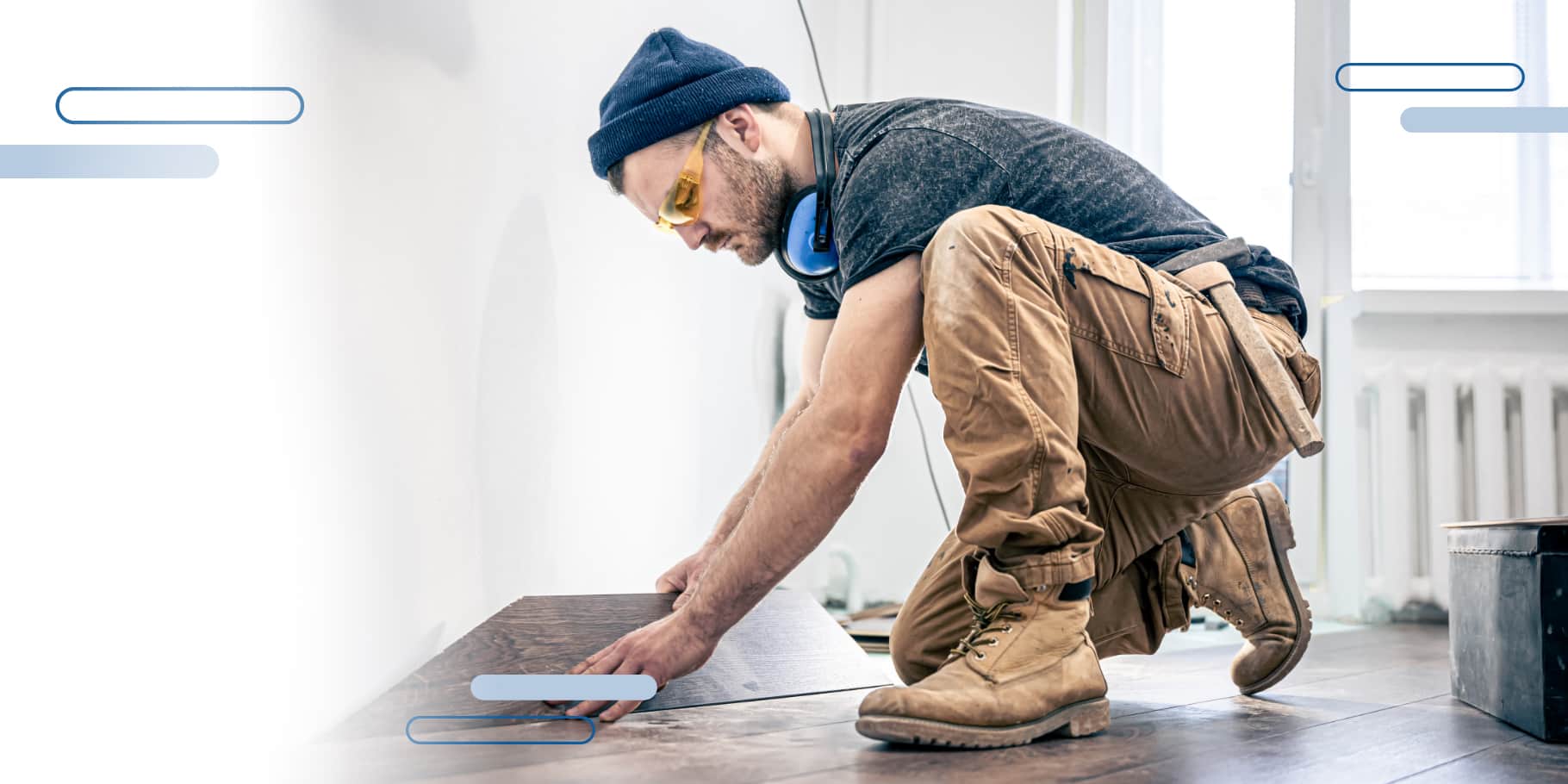 A construction worker laying hard wood floors inside a home.