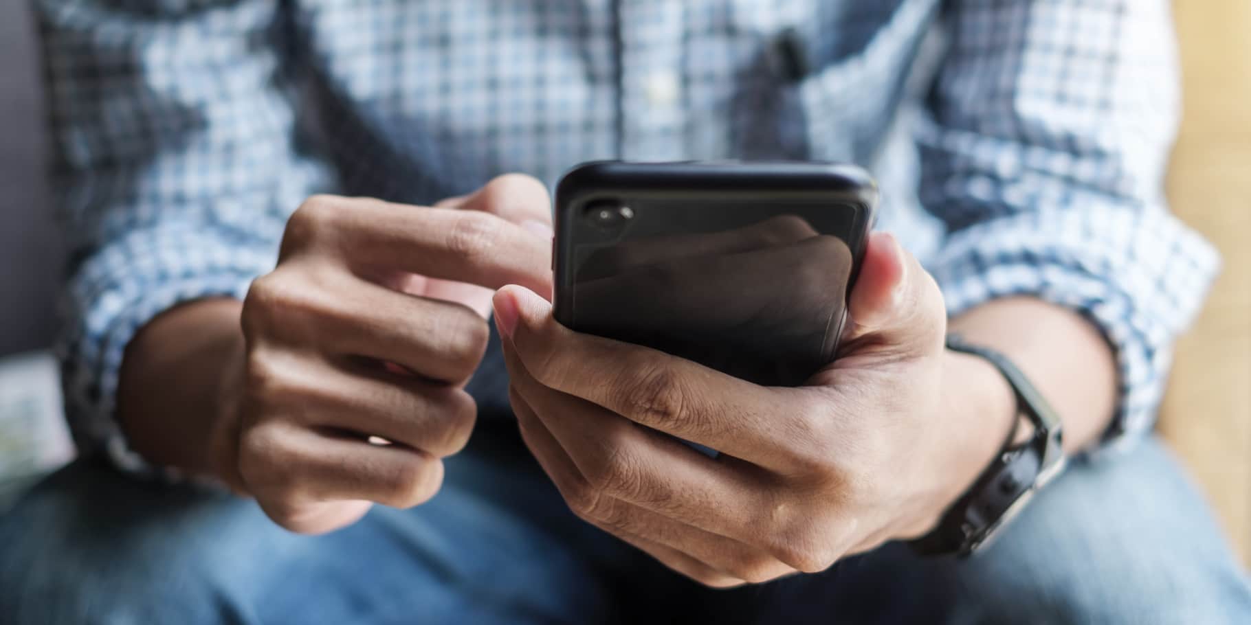 Masculine hands holding a mobile phone.